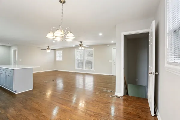 a view of a big room with wooden floor and windows