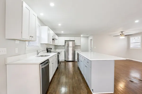 a kitchen with white cabinets sink and stove
