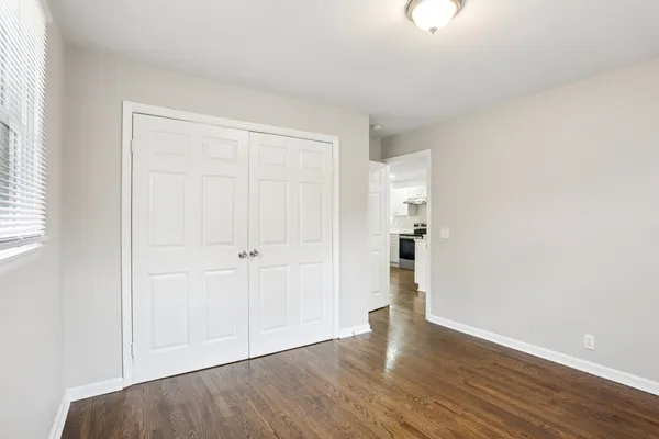 an empty room with wooden floor & windows