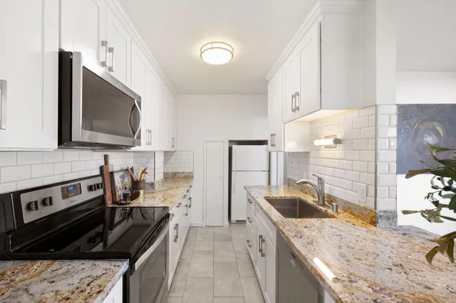 a kitchen with stainless steel appliances granite countertop a sink stove and refrigerator
