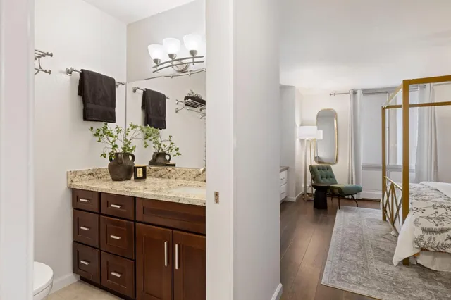 a en suite bathroom with a granite countertop sink and mirror