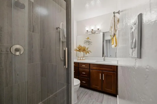 a bathroom with a granite countertop sink a mirror a vanity and a shower