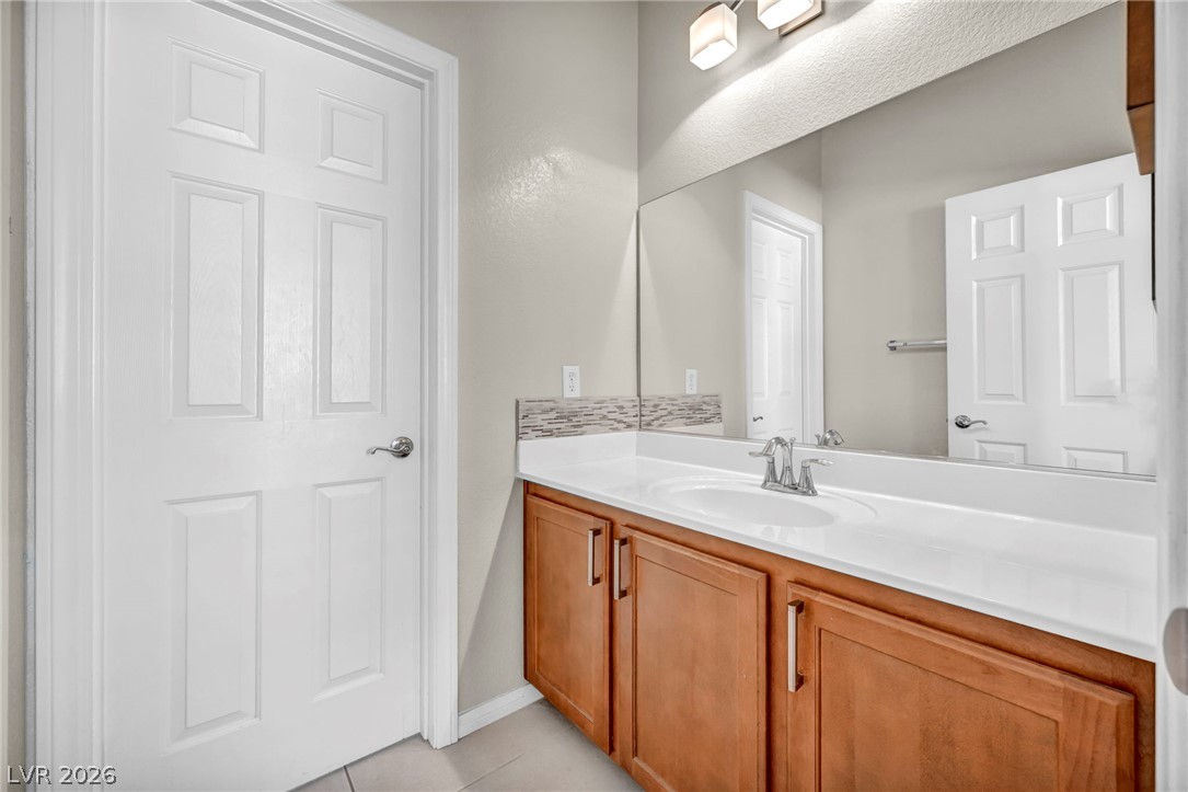 389 Fringe Ruff Drive Las Vegas, NV 89148 - Photo 28 of 53 An integrated vanity countertop and wood cabinetry anchor this clean guest bathroom.
