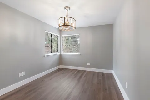 a view of big room with wooden floor chandelier and windows