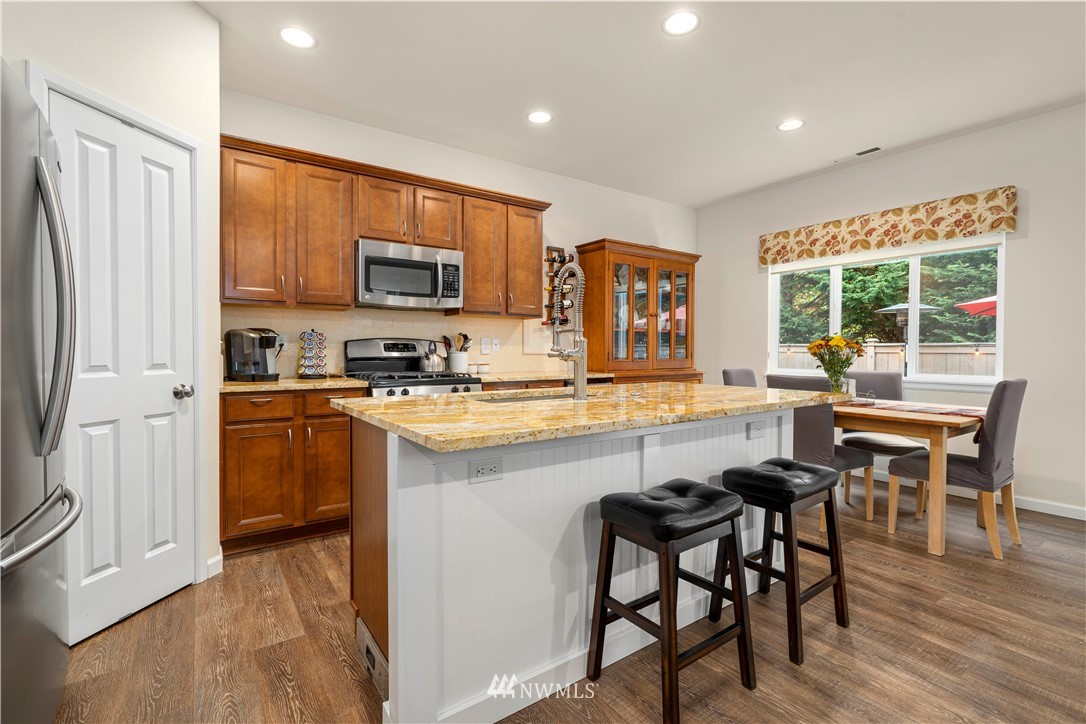 3032 183rd Place Southeast Bothell, WA 98012 - Photo 4 of 21 a kitchen with stainless steel appliances granite countertop a stove a sink a microwave a refrigerator white cabinets and wooden floor