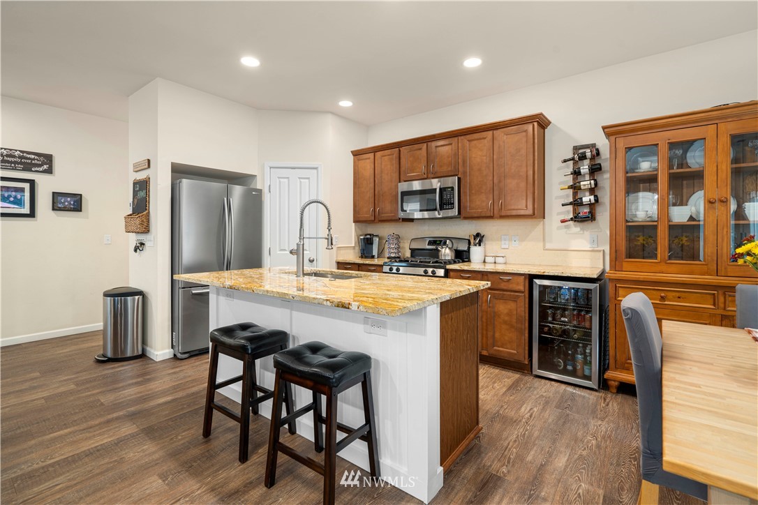 3032 183rd Place Southeast Bothell, WA 98012 - Photo 6 of 21 a kitchen with stainless steel appliances granite countertop a stove a sink dishwasher a refrigerator with a dining table and chairs with wooden floor