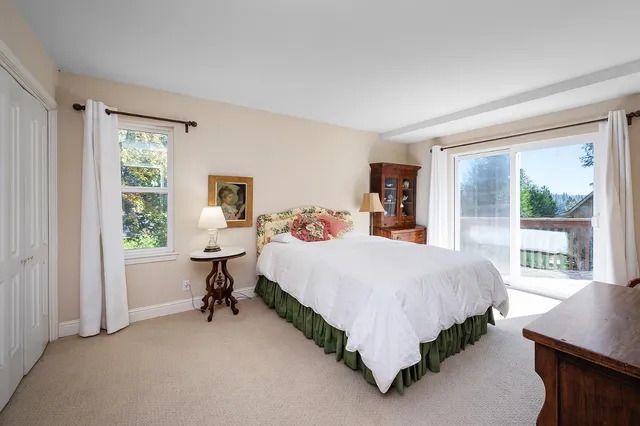 a bedroom with a bed and large windows