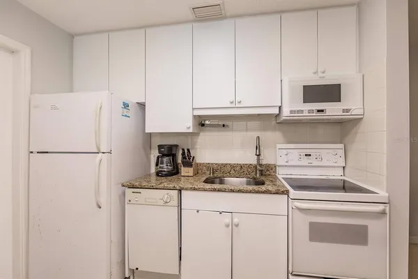 a kitchen with appliances a refrigerator and cabinets