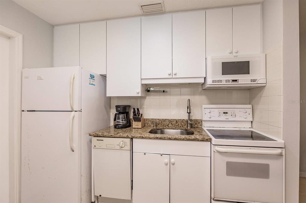 6020 Midnight Pass Road, Unit 59 Sarasota, FL 34242 - Photo 4 of 12 a kitchen with appliances a refrigerator and cabinets