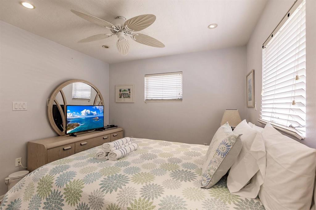 6020 Midnight Pass Road, Unit 59 Sarasota, FL 34242 - Photo 7 of 12 a bedroom with a bed and a flat screen tv