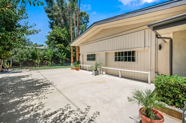a backyard of a house with table and chairs and potted plants