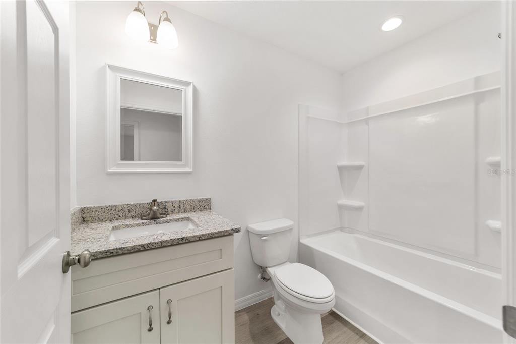13078 Northeast 7th Loop Silver Springs, FL 34488 - Photo 34 of 56 a bathroom with a granite countertop sink a toilet and a bathtub