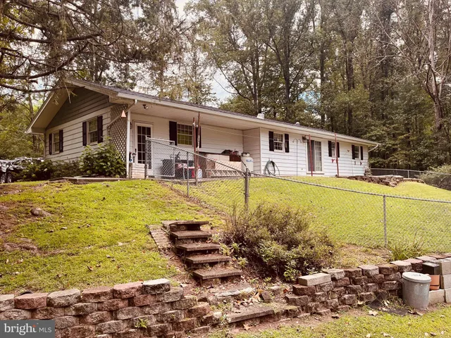 a view of a house with swimming pool lawn chairs and a yard