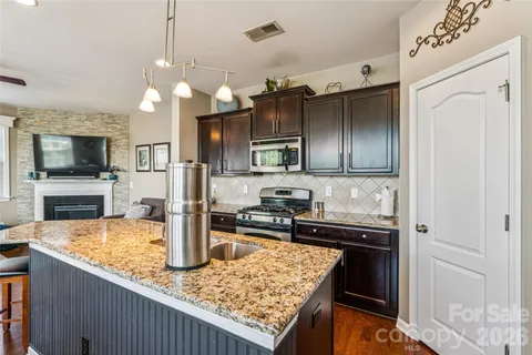 a kitchen with stainless steel appliances granite countertop a sink a stove and a refrigerator
