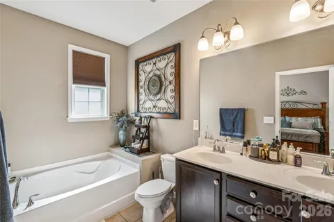 a bathroom with a granite countertop sink a toilet a mirror and shower