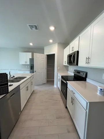 a large kitchen with a stove top oven a sink a microwave and cabinets