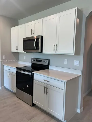 a kitchen with white cabinets and black appliances