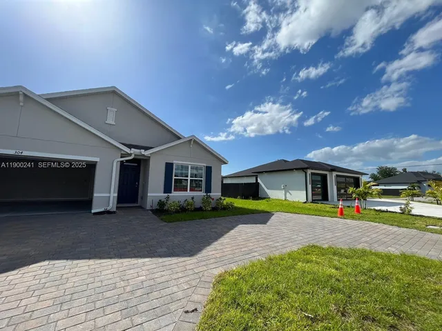 a view of a house with a yard and potted plants