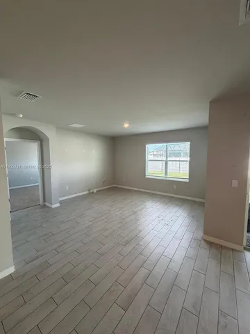 a view of empty room with window and wooden floor