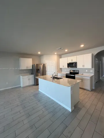 a large kitchen with kitchen island a sink a counter top stainless steel appliances and cabinets