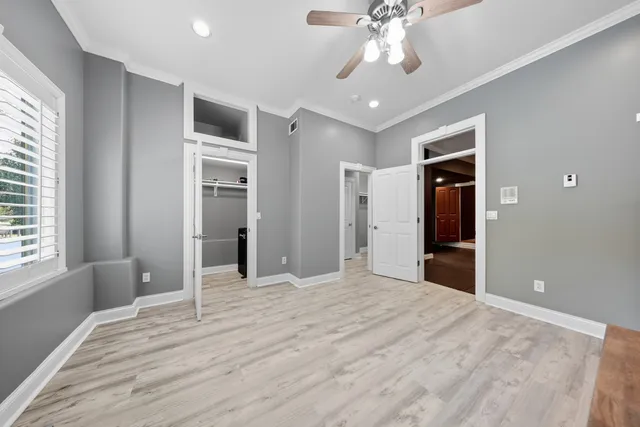 a view of empty room with wooden floor and fan