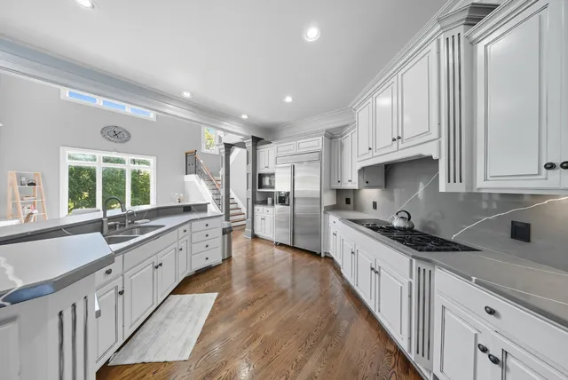 a large kitchen with granite countertop a large counter top a sink stainless steel appliances and cabinets