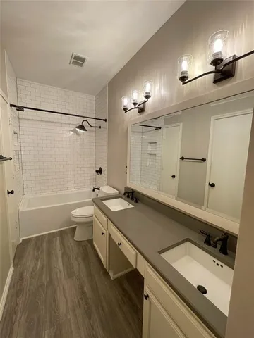 a bathroom with a granite countertop sink a toilet a mirror and shower