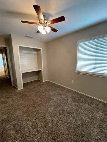 an empty room with closet and a ceiling fan