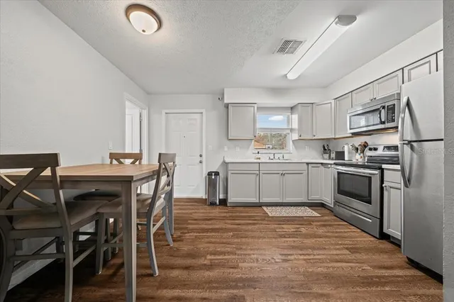 a kitchen with cabinets wooden floor and stainless steel appliances