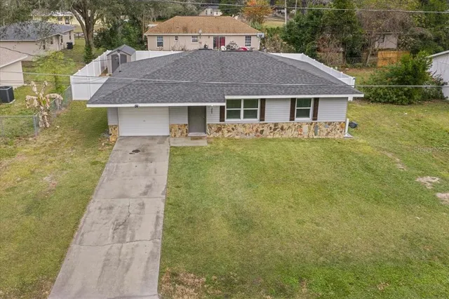 a aerial view of a house next to a yard with plants and large trees