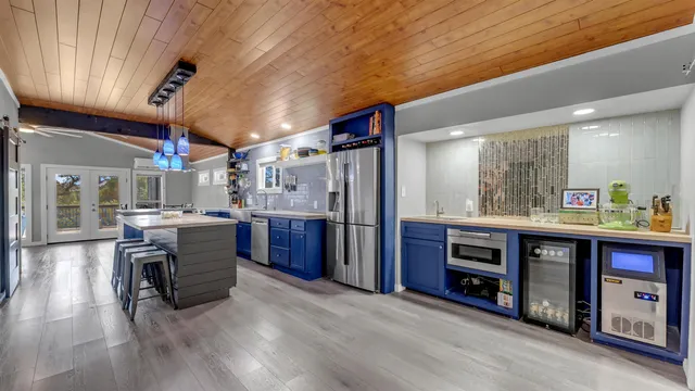 a view of kitchen with stainless steel appliances granite countertop a refrigerator a sink dishwasher a oven and a dining table with wooden floor