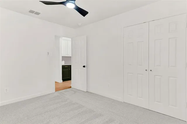 an empty room with a ceiling fan and carpet