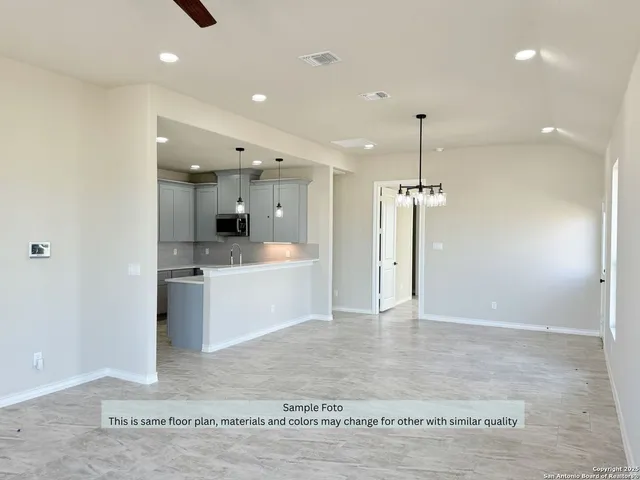 a large kitchen with a refrigerator a sink dishwasher a stove and white cabinets with wooden floor