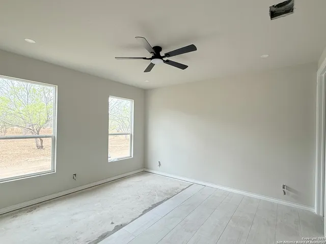 an empty room with windows and fan