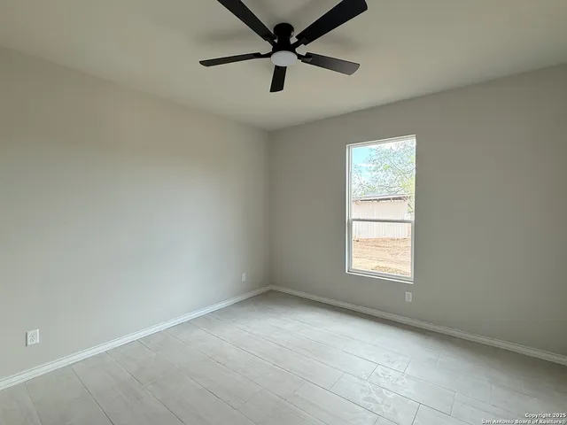 an empty room with a window and a fan