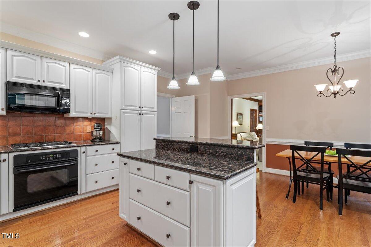 12329 Whartons Way Raleigh, NC 27613 - Photo 8 of 51 a kitchen with granite countertop a stove a sink a dining table and chairs with wooden floor