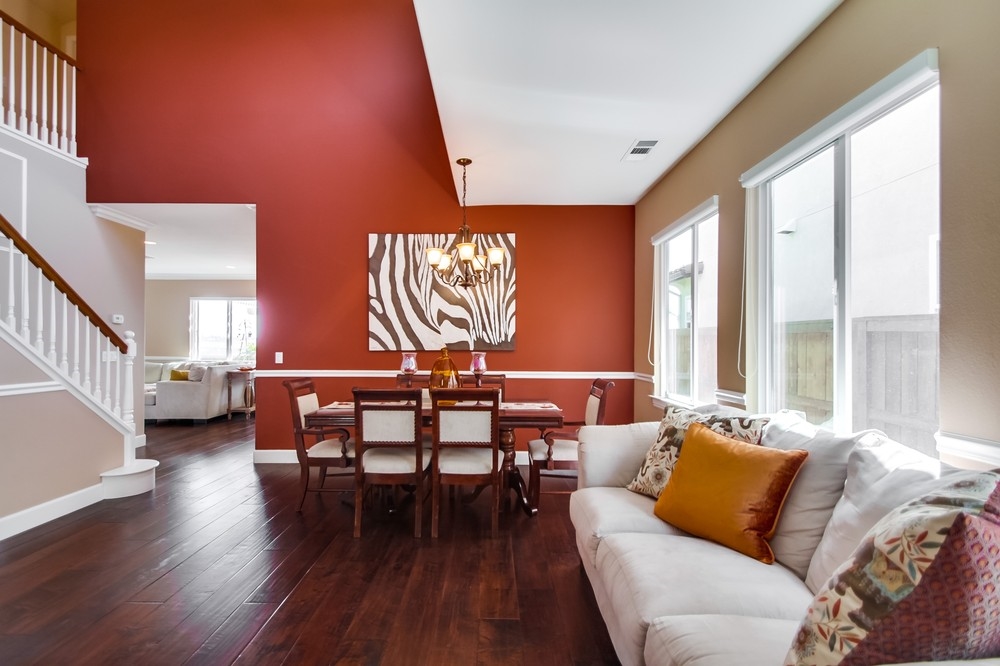 4751 Crater Rim Road Carlsbad, CA 92010 - Photo 5 of 25 A sweeping 2 story atrium style living/dining room greets guests, warmly embued with maple plank handscraped hardwood flooring, wainscoating, crown molding & warm Fall colored accent walls.