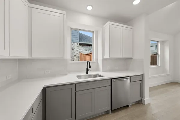 a kitchen with white cabinets and sink