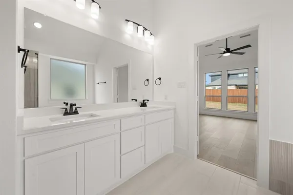 a bathroom with a double vanity sink mirror and next to a window