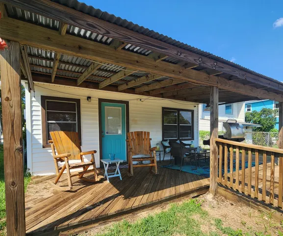a view of a patio with table and chairs with wooden floor and fence