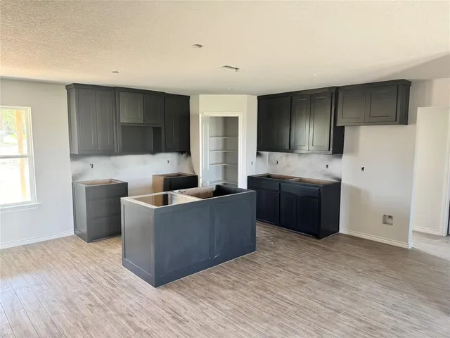 a living room with stainless steel appliances kitchen island granite countertop a sink and a refrigerator