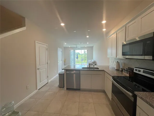a kitchen with stainless steel appliances granite countertop a sink and a stove top oven with wooden floor