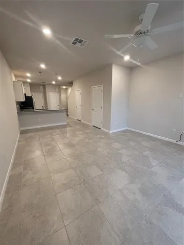 an empty room with a ceiling fan & windows