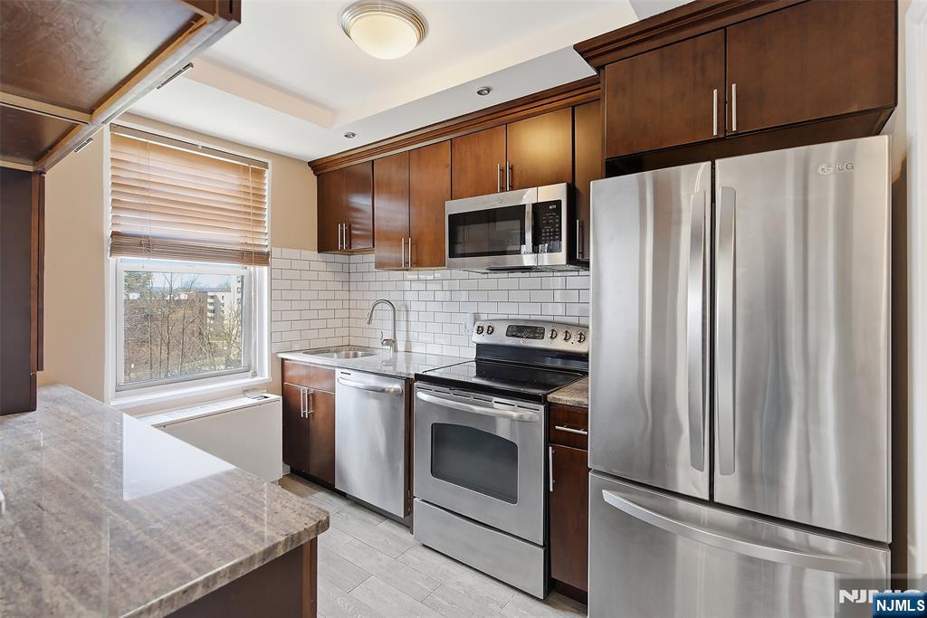 301 Beech Street, Unit 9K Hackensack, NJ 07601 - Photo 13 of 24 a kitchen with stainless steel appliances granite countertop a refrigerator sink and stove