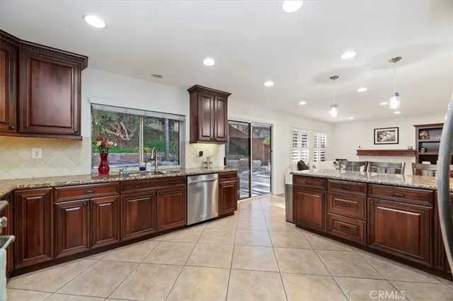 a large kitchen with stainless steel appliances granite countertop wooden cabinets a sink dishwasher and a stove