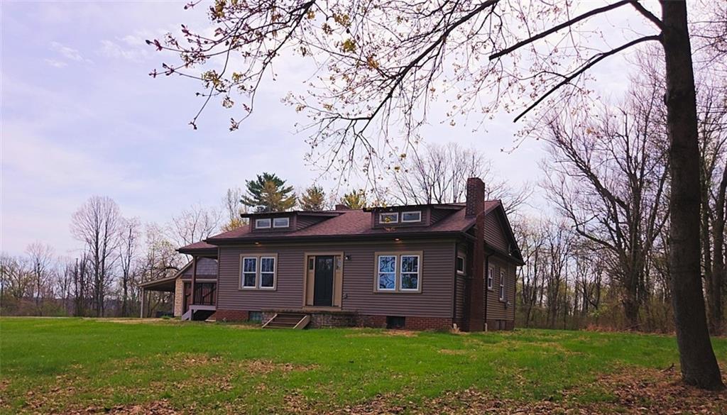 a brick house with a large tree and a yard in front of it