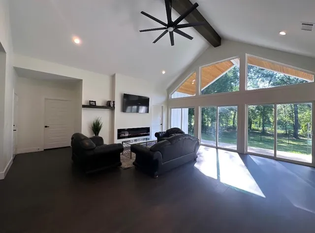 a living room with furniture a ceiling fan and a large window