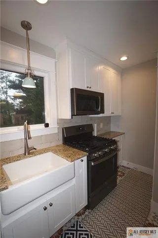 a kitchen with granite countertop a sink and a stove top oven