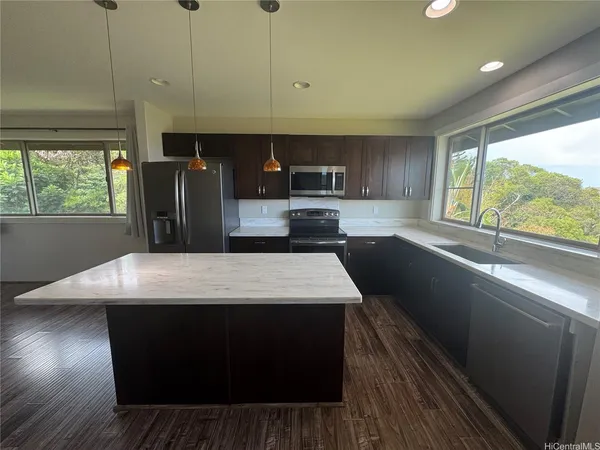 a kitchen with stainless steel appliances granite countertop a sink a stove a refrigerator a sink with wooden cabinets and wooden floor