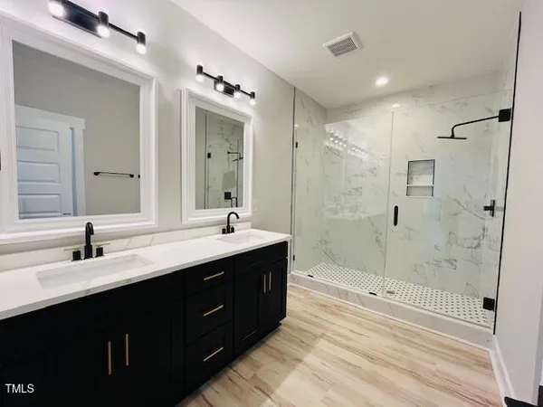 a bathroom with a double vanity sink mirror double shower and a